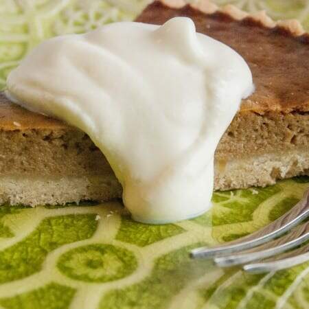 A slice of pumpkin pie topped with whipped cream on a green embossed plate.
