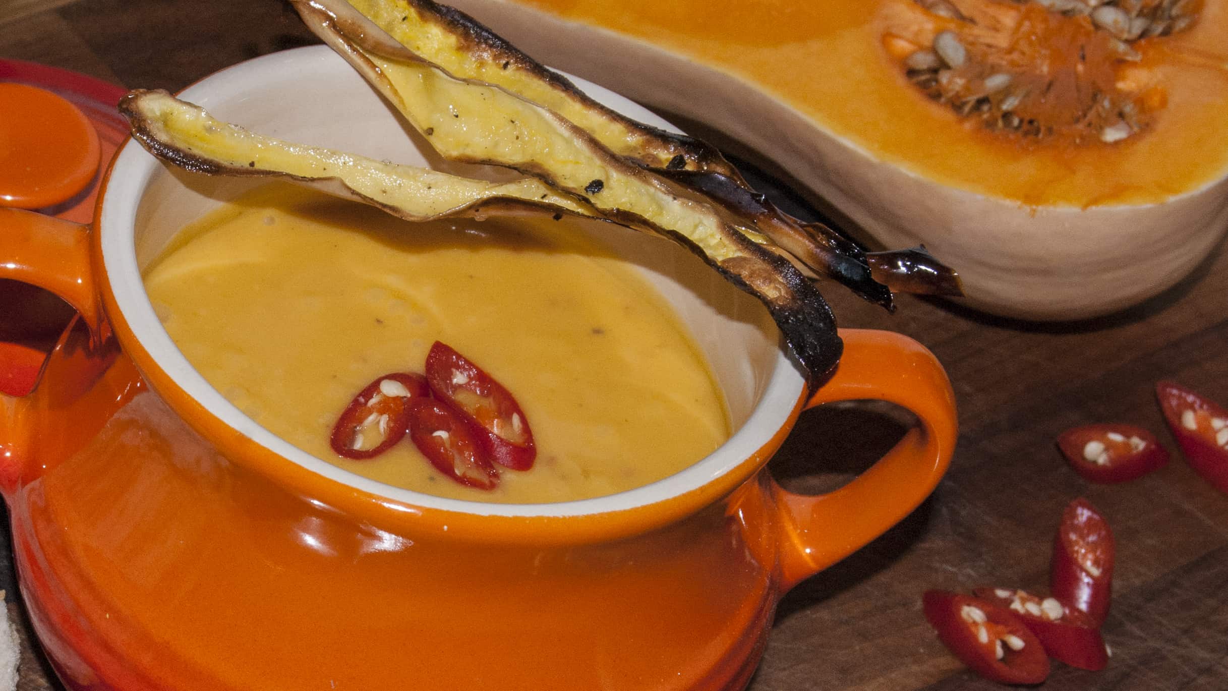 pumpkin spiced soup topped with chillies in an orange le crueset soup terrine