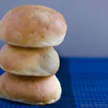 A stack of 3 brioche rolls on royal blue backdrop.