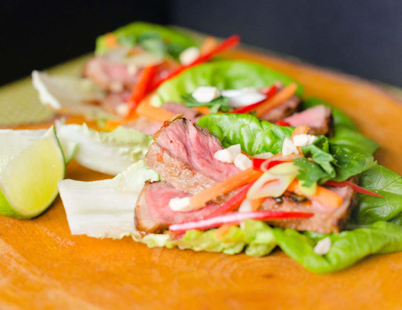 Sirloin steak with lemongrass marinade served on a lettuce leaf with lime and peanuts to garnish