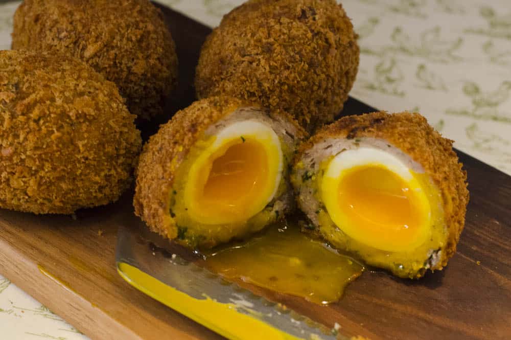 a board of scotch eggs, perfectly cooked inside with one cut open