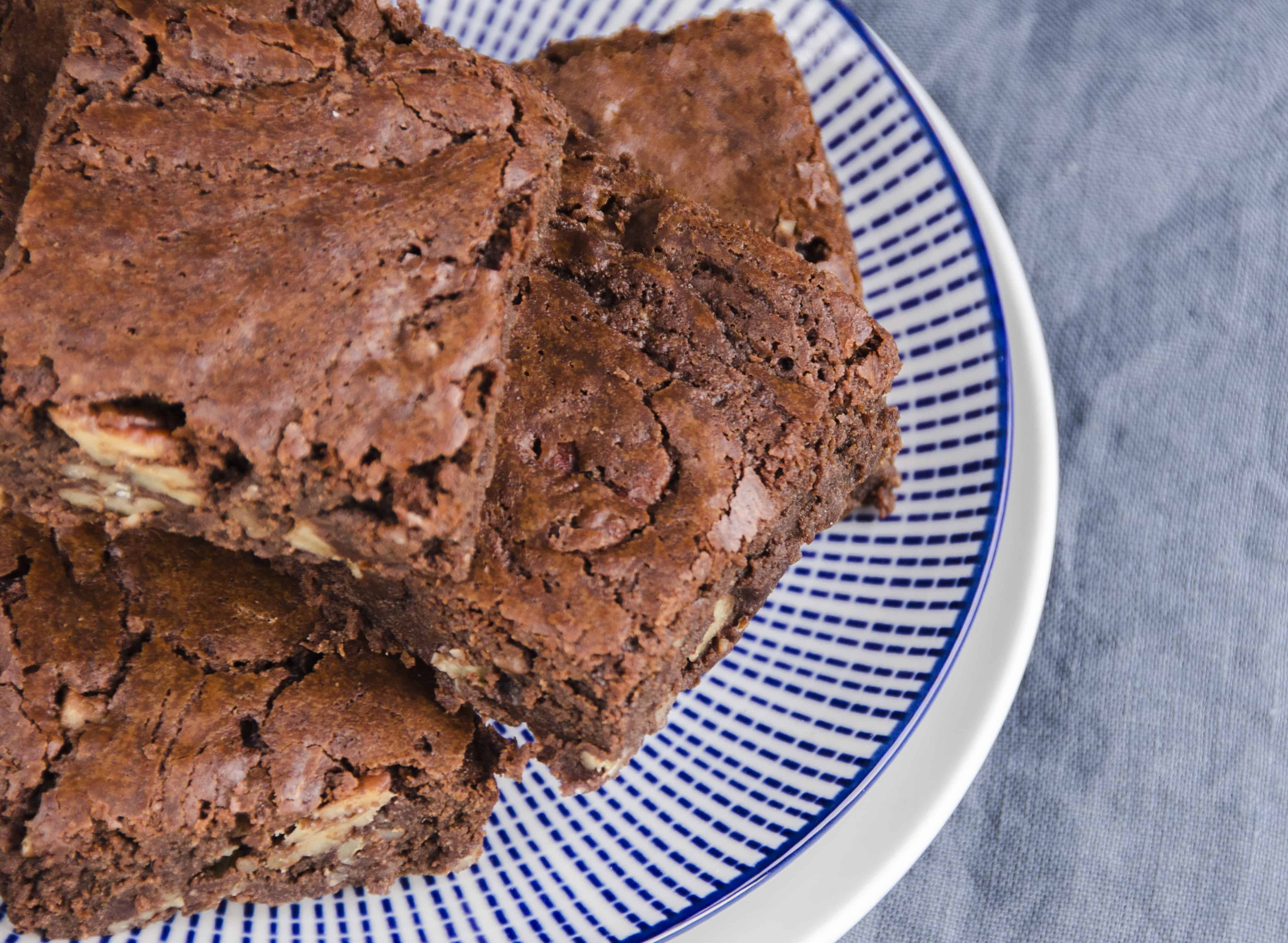 chocolate and pecan brownies on a blue striped plate a top down view