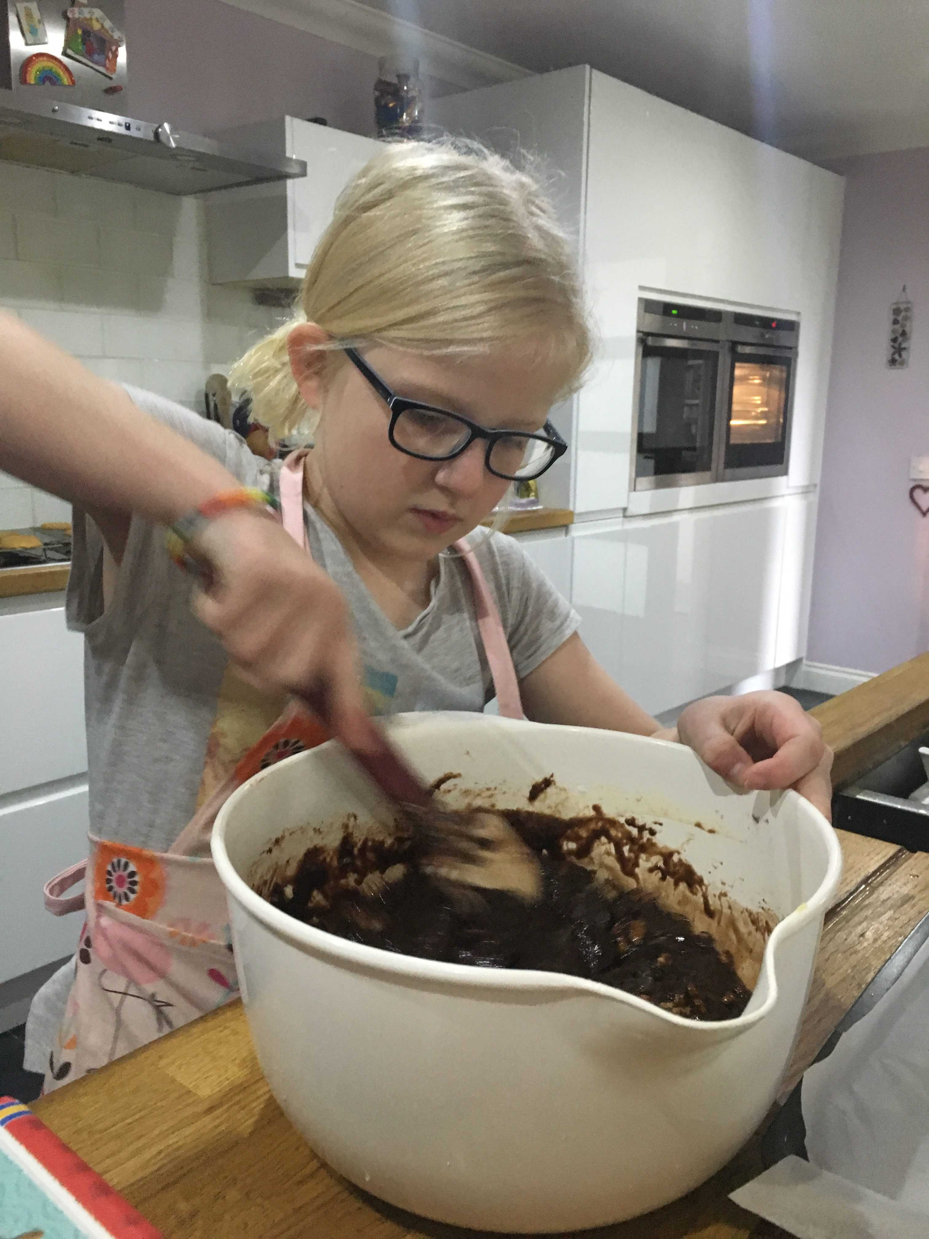 Young girl concentrating on mixing brownies