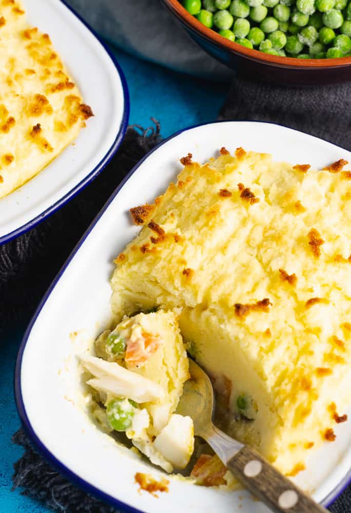 fish pie topped with mashed potatoes with a spoon taking the first bite