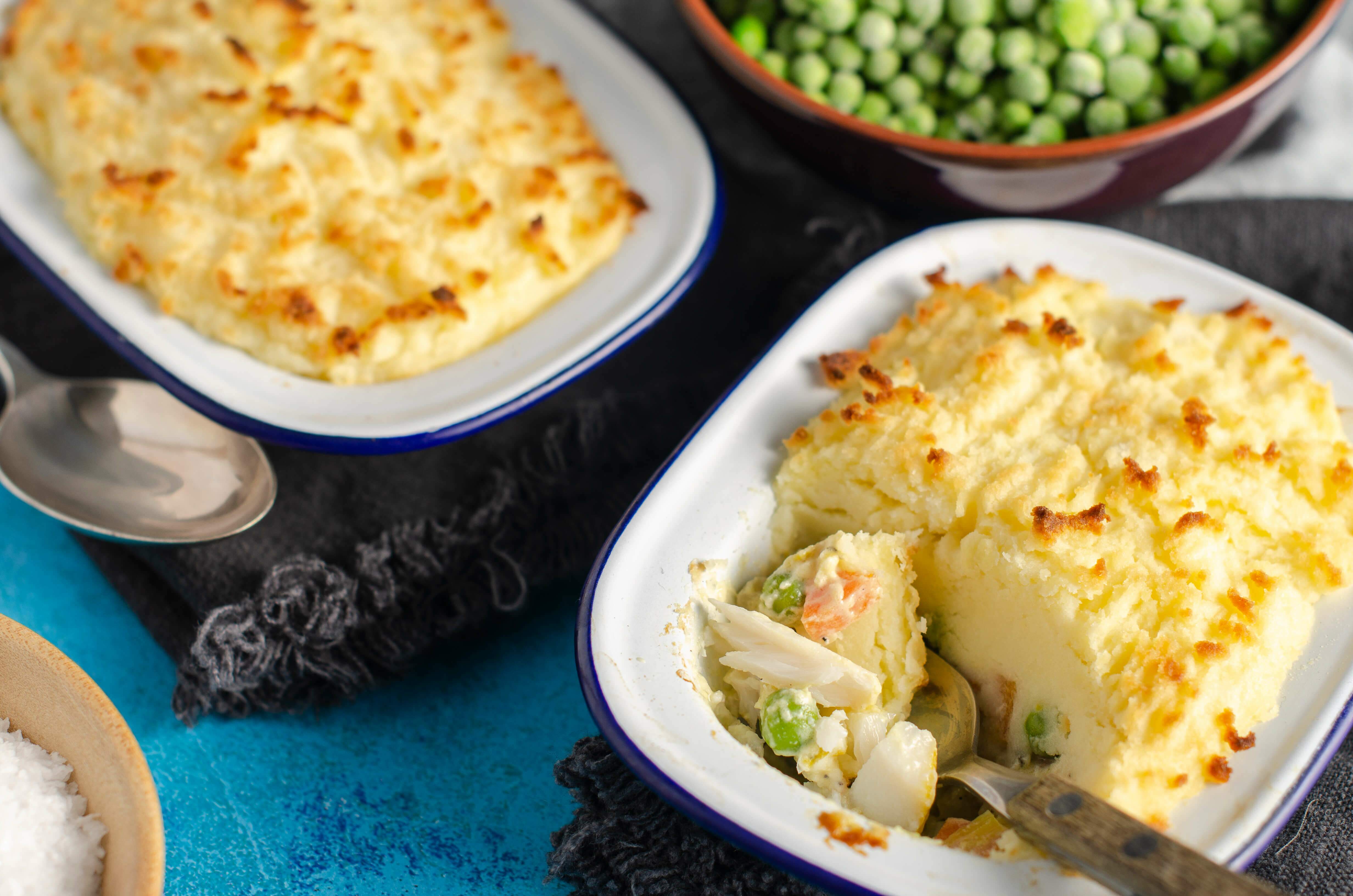 A fish pie dinner for two on a ocean blue background and navy blue napkins