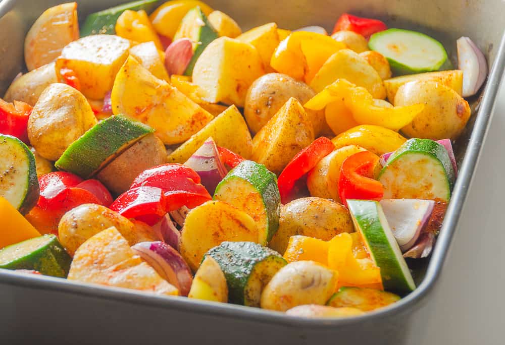 cajun chicken vegetables prepped with seasoning in pan ready for oven