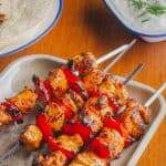 lemon paprika chicken kebabs ready for eating with dip and wraps in back