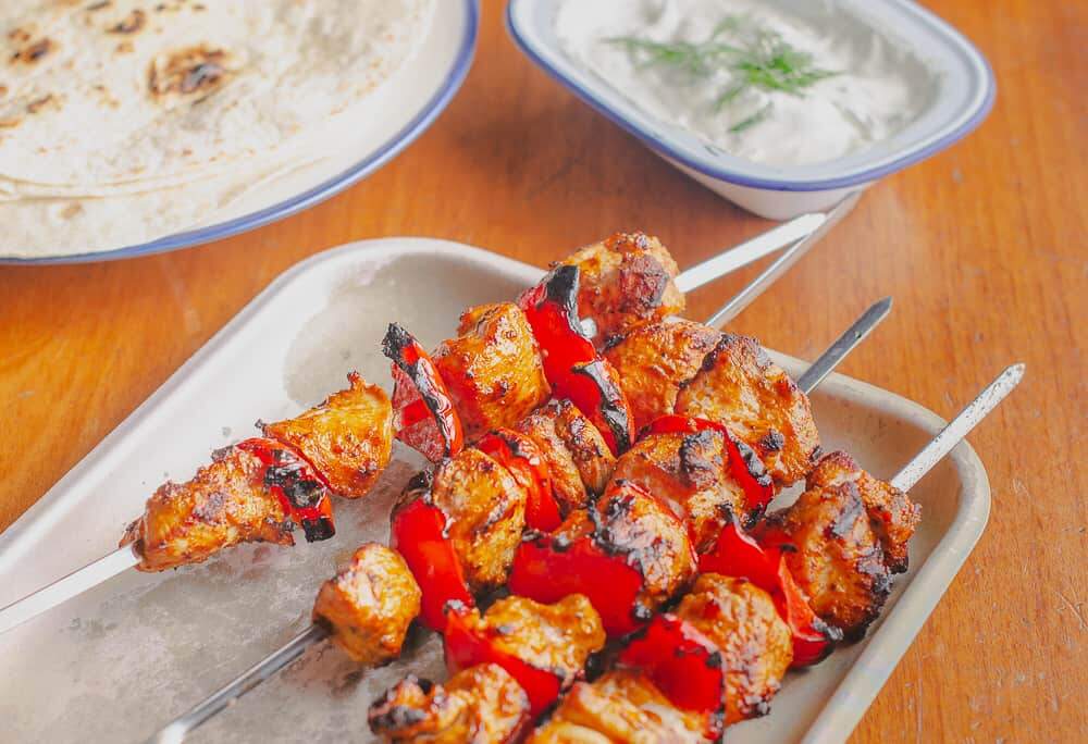 portrait version of lemon and paprika chicken kebabs with dill dip and wraps to the back