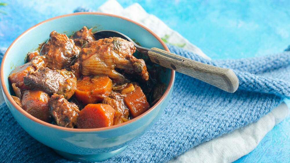 a closeup of a bowl of smoked paprika beef on a blue napkin and blue background