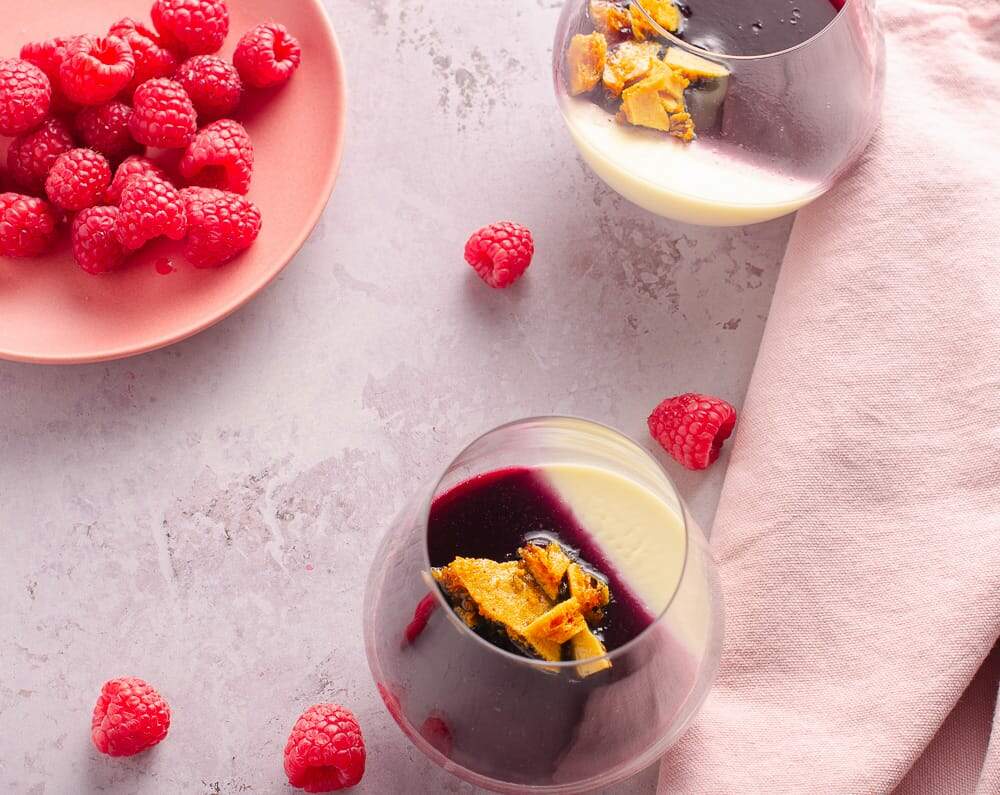 two summer desserts of lemon panncotta, raspberry jelly topped with honeycomb and a plate of fresh raspberries.