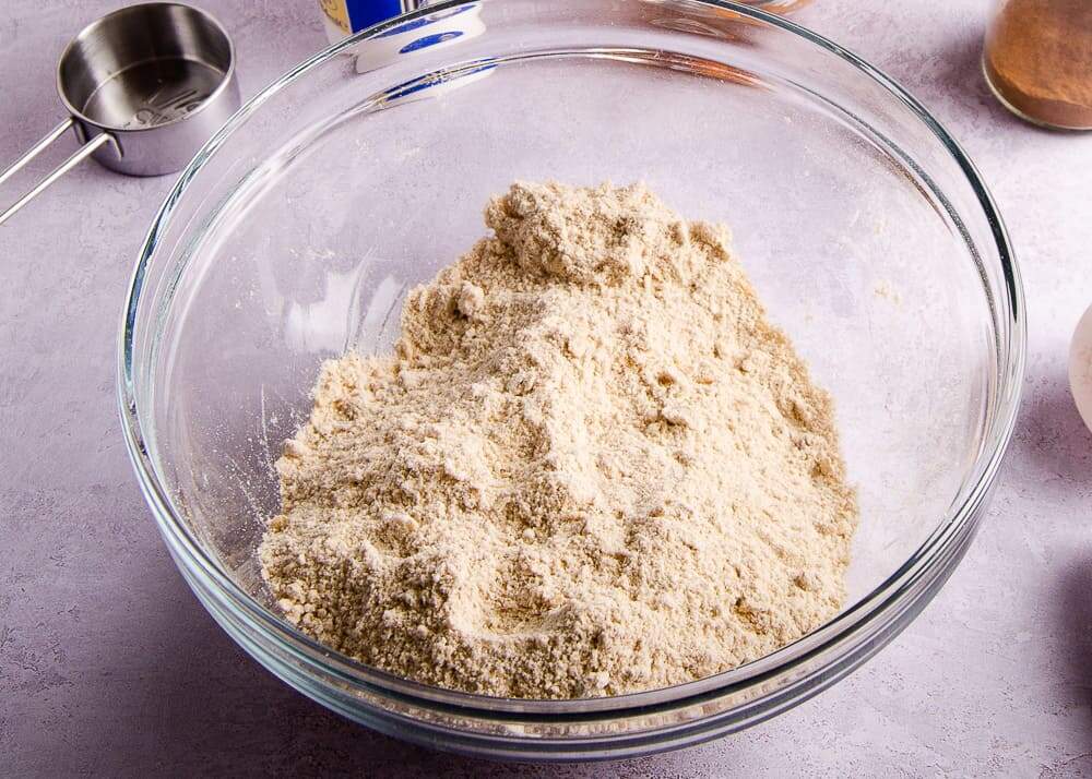 A glass bowl showing flour and cold butter rubbed together as the start of making scones to show how the texture should be that of breadcrumbs.