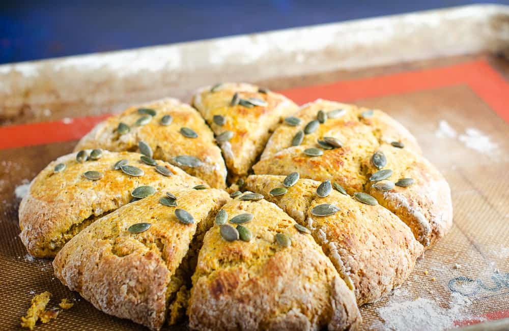 A batch of pumpkin spied scones fresh from the oven on top of a non stick silicone mat and dusted with flour.