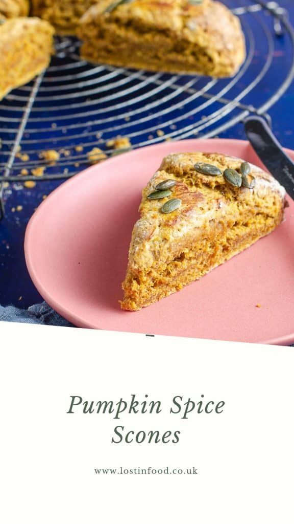 A close up view of a pumpkin spice scone on a pink plate ready to eat and the rest of the scones blurred in the back as well as a large white border to the bottom with the name Pumpkin Spice Scone and Lost in Food as the author.