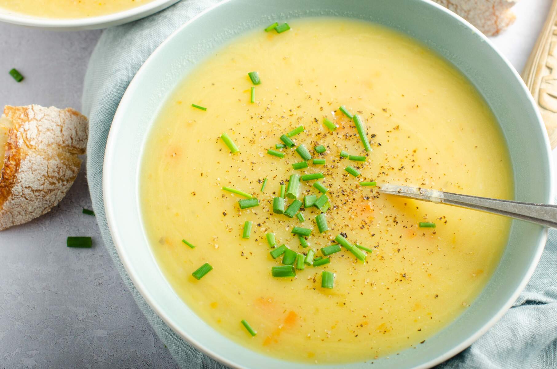 A warming bowl of leek and potato soup with some crusty bread and topped with fresh chopped chives.