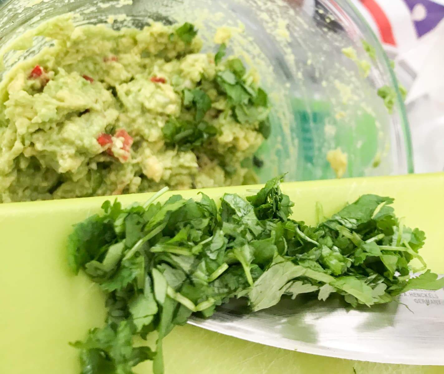 Adding fresh chopped coriander (cilantro) to smashed avocado, chillies and spring onions to make guacamole.