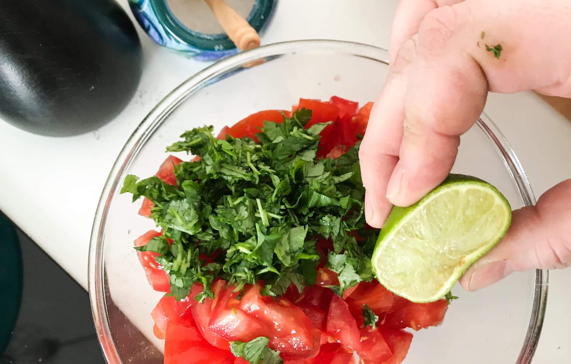 adding fresh squeezed lime juice to the chopped tomatoes for the fresh tomato salsa.