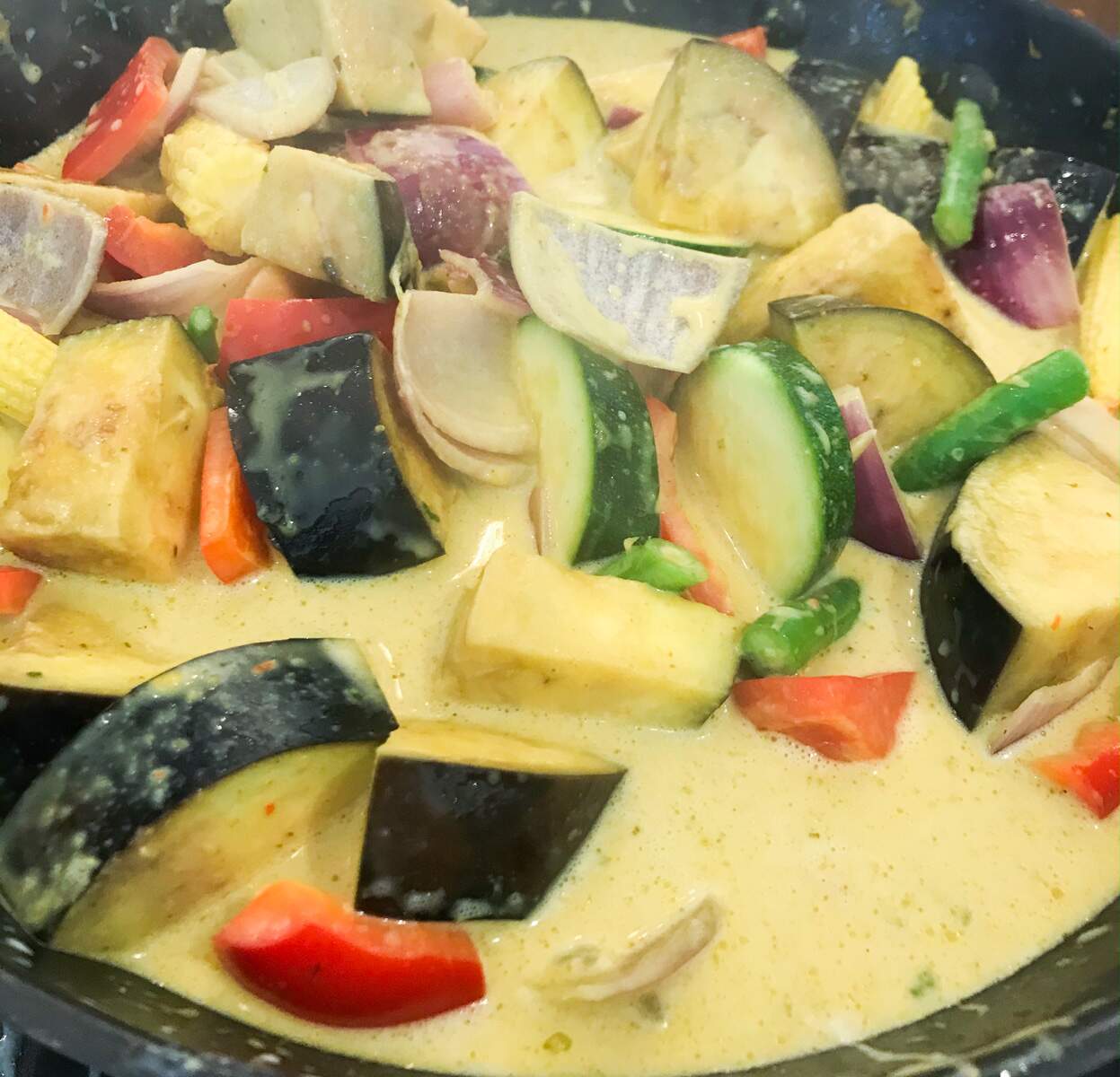 A steaming pan of vegetable and coconut curry almost cooked and ready to serve.