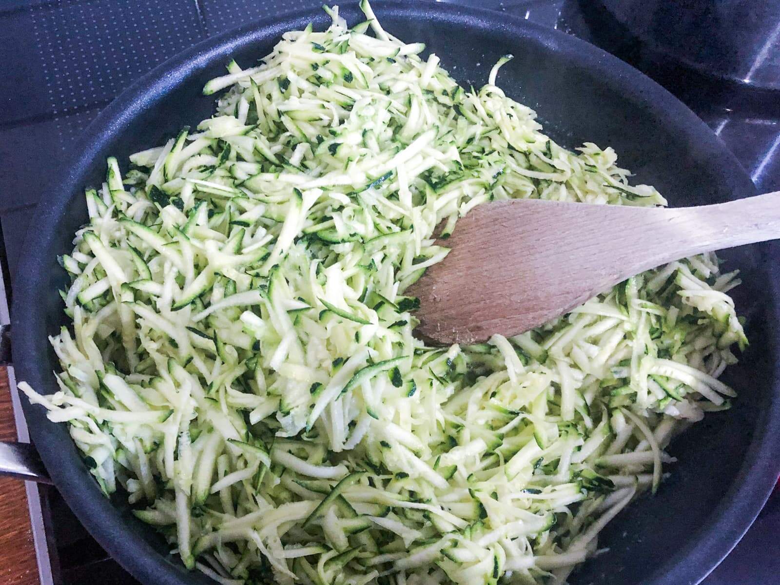 Grated courgette being fried off in a pan