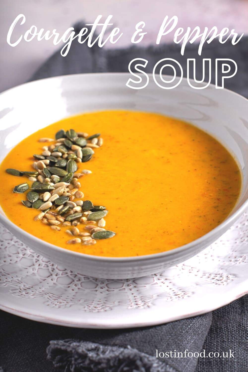 A bowl of courgette and pepper soup topped with toasted seeds.