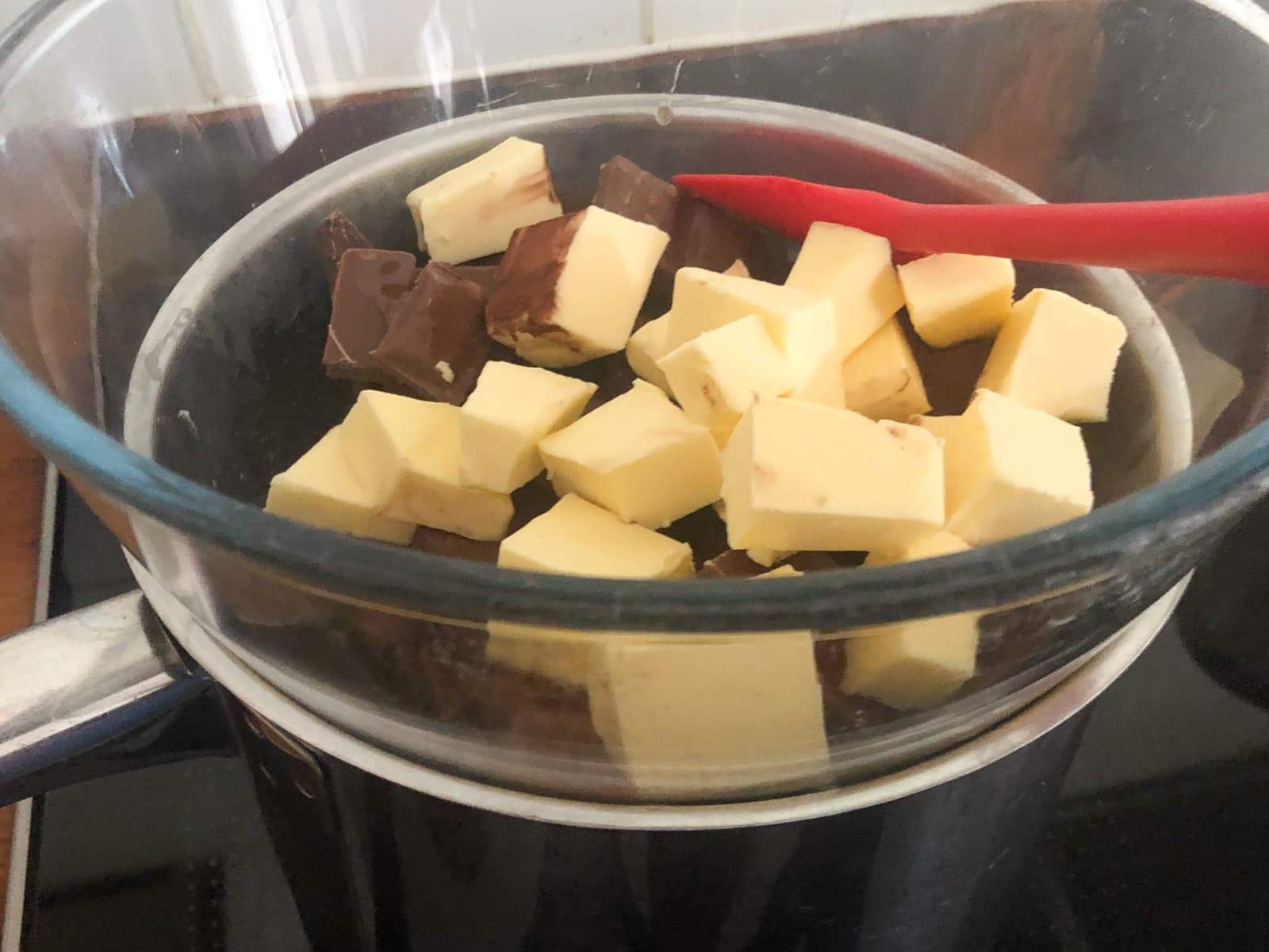 Butter and chocolate being melted in a glass bowl over simmering water.