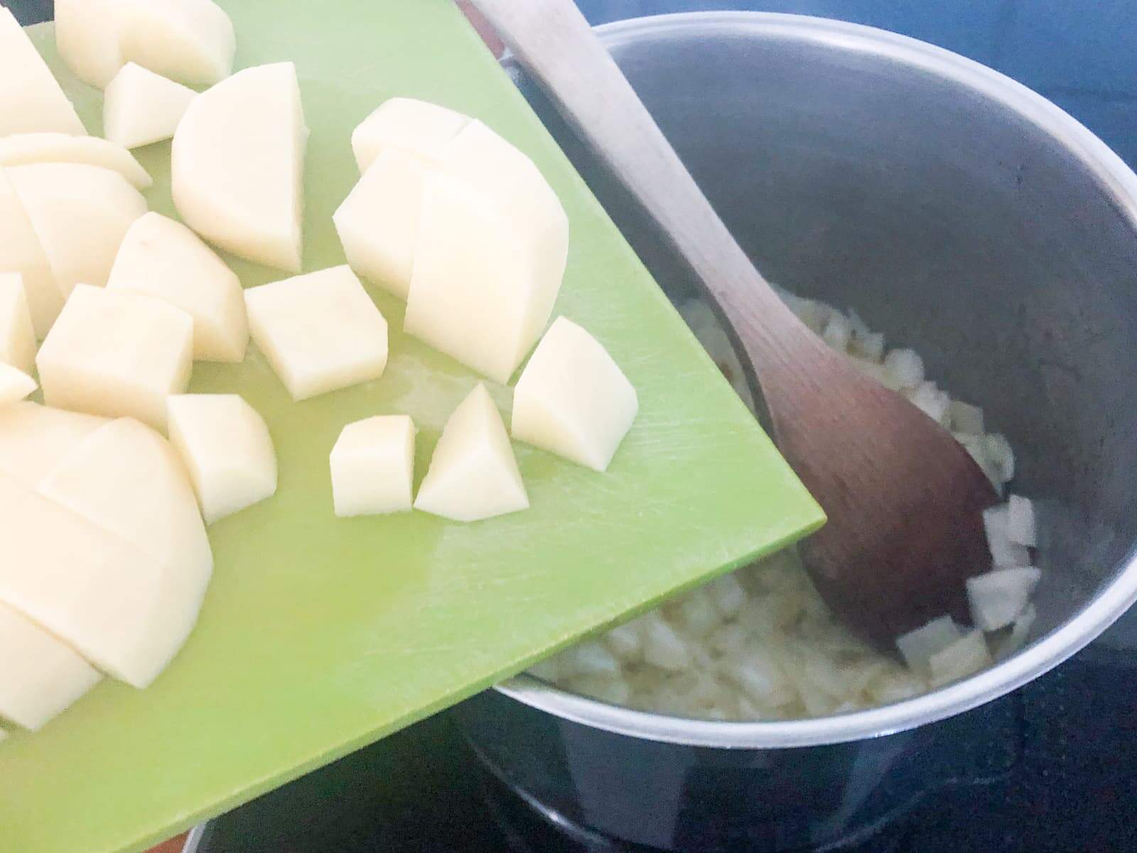 A pan with onions fried off and now adding chopped potatoes to make soup.