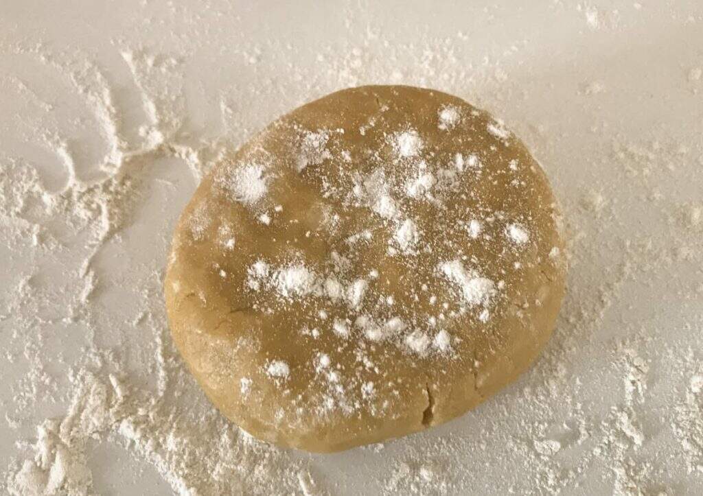 A ball of shortcrust pastry topped with a sprinkling of flours ready to be rolled out to fill a tart case.