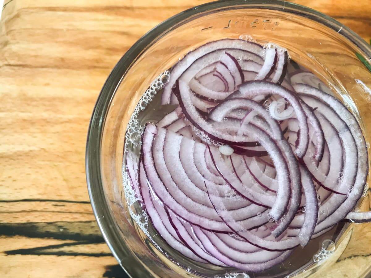 Sliced red onions in boiling water before using in a salad
