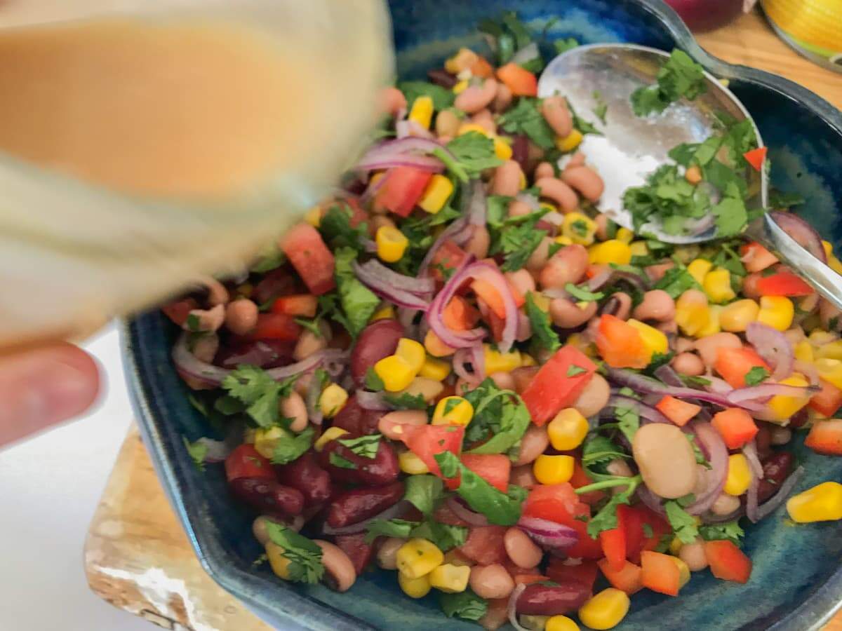 adding a vinaigrette dressing to a mixed bean salad.