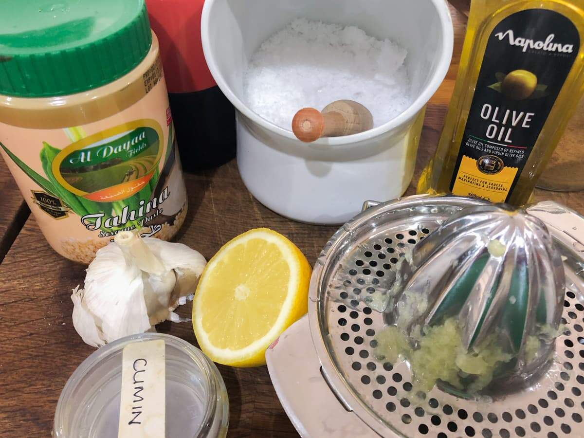 Ingredients to make hummus laid out on a wooden board.