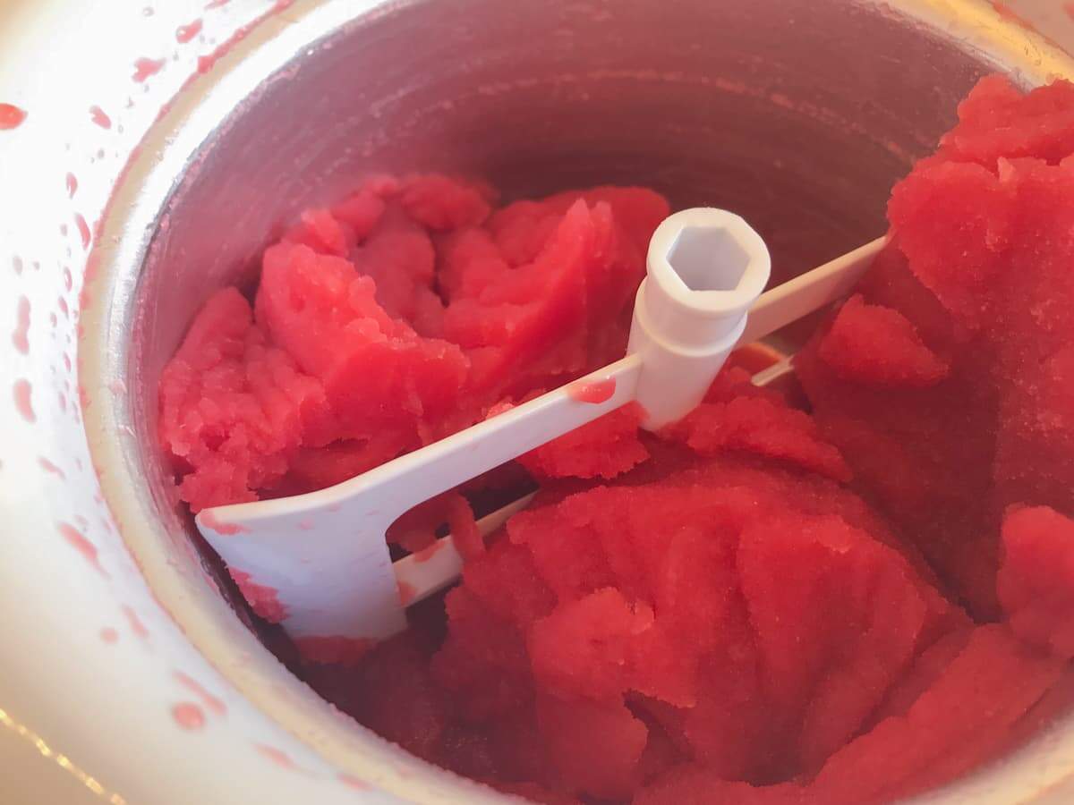 Blood orange sorbet finished churning in an ice cream machine and ready for the freezer.