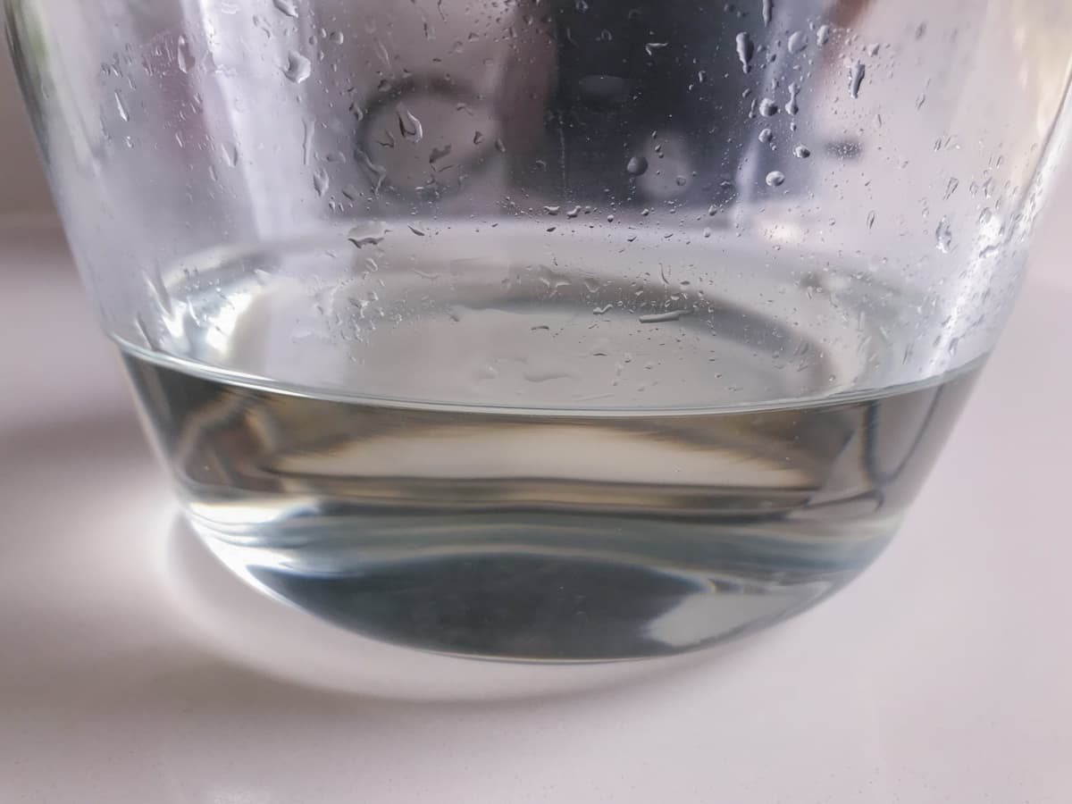 Sugar syrup in a glass bowl sitting on a white marble surface