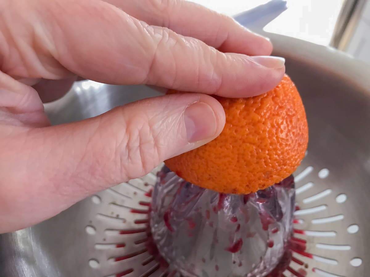 A hand juicing blood oranges.