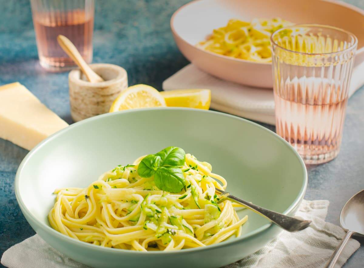 Courgette linguine with lemon and basil in a pale green bowl.