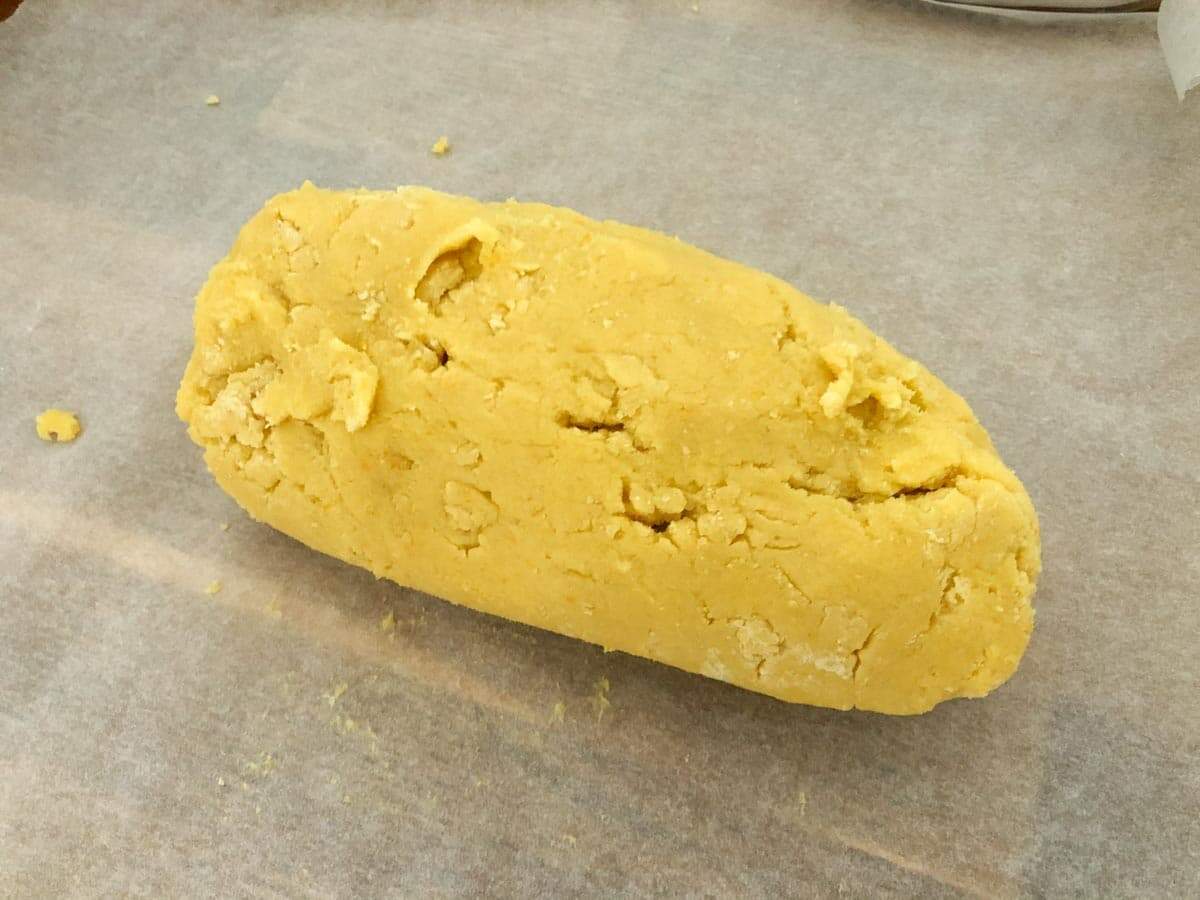 Orange biscuit dough rolled into a sausage shape and ready to be chilled.