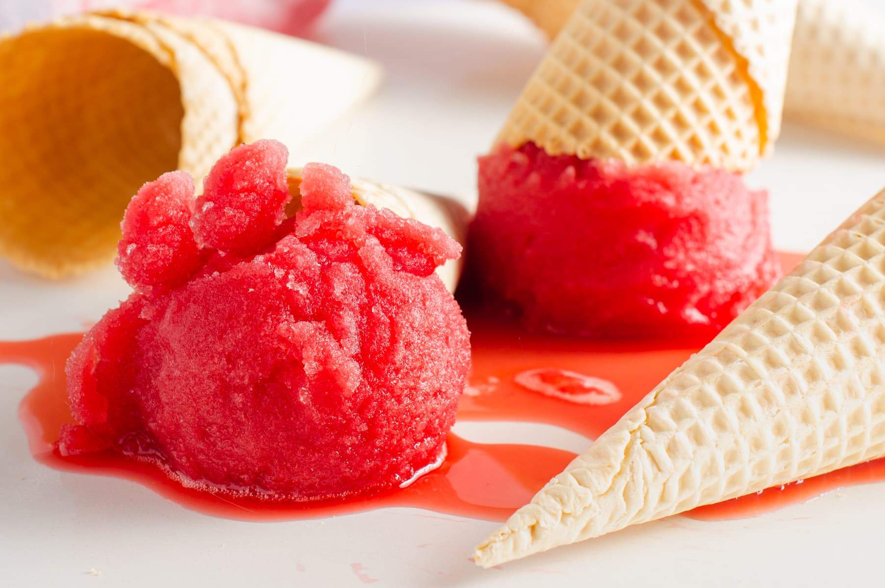 Blood orange sorbet melting on a white marble surface