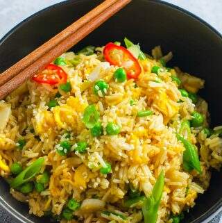 A large black bowl sat on a dark grey linen napkin filled with egg fried rice.