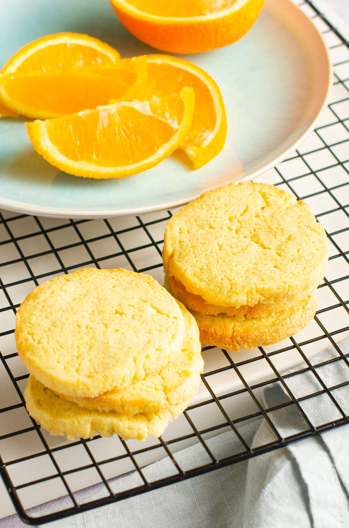 Orange butter cookies on a cooling rack and a sliced orange.