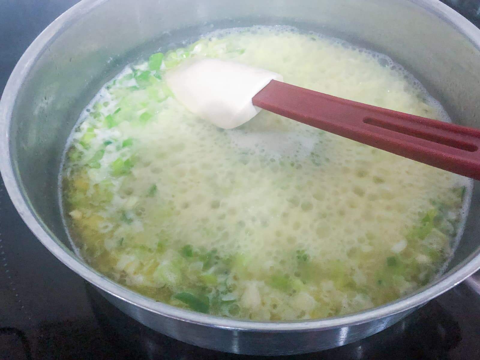 A pan with butter sautéing with spring onions and garlic
