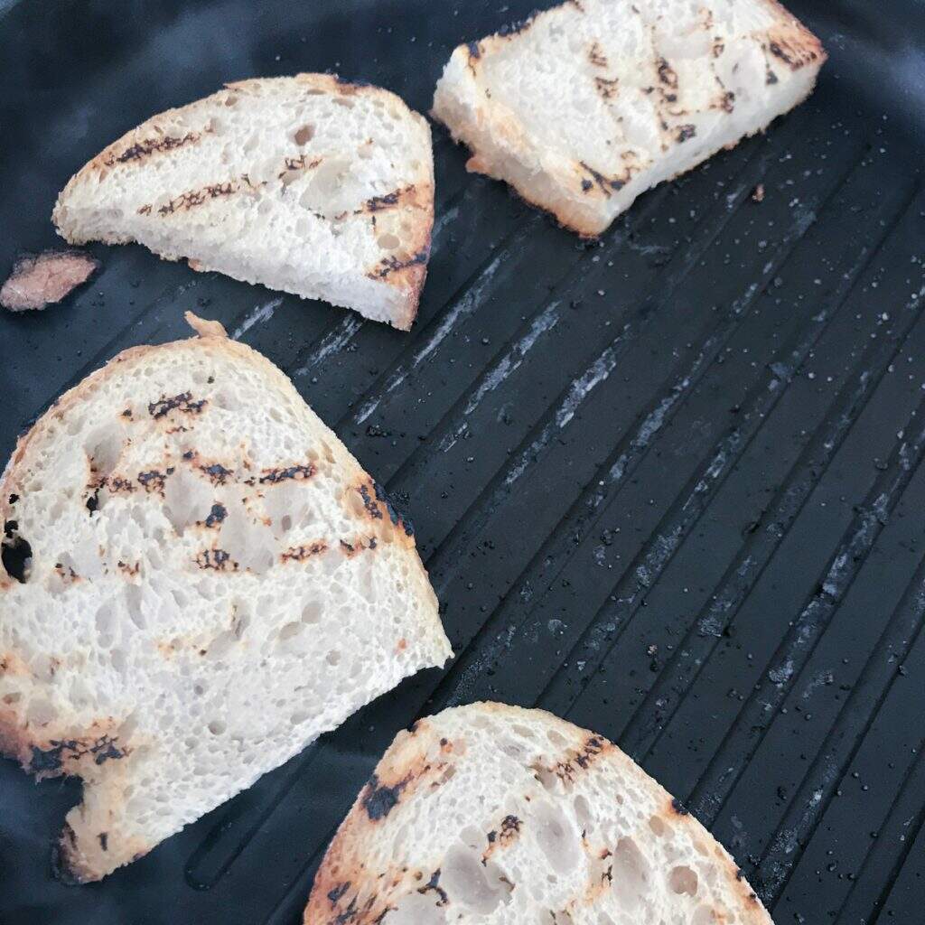 sourdough sliced bread toasting on a grill pan.