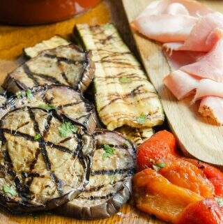 Antipasti board of marinated eggplant, zucchini, and peppers with olives and bread.