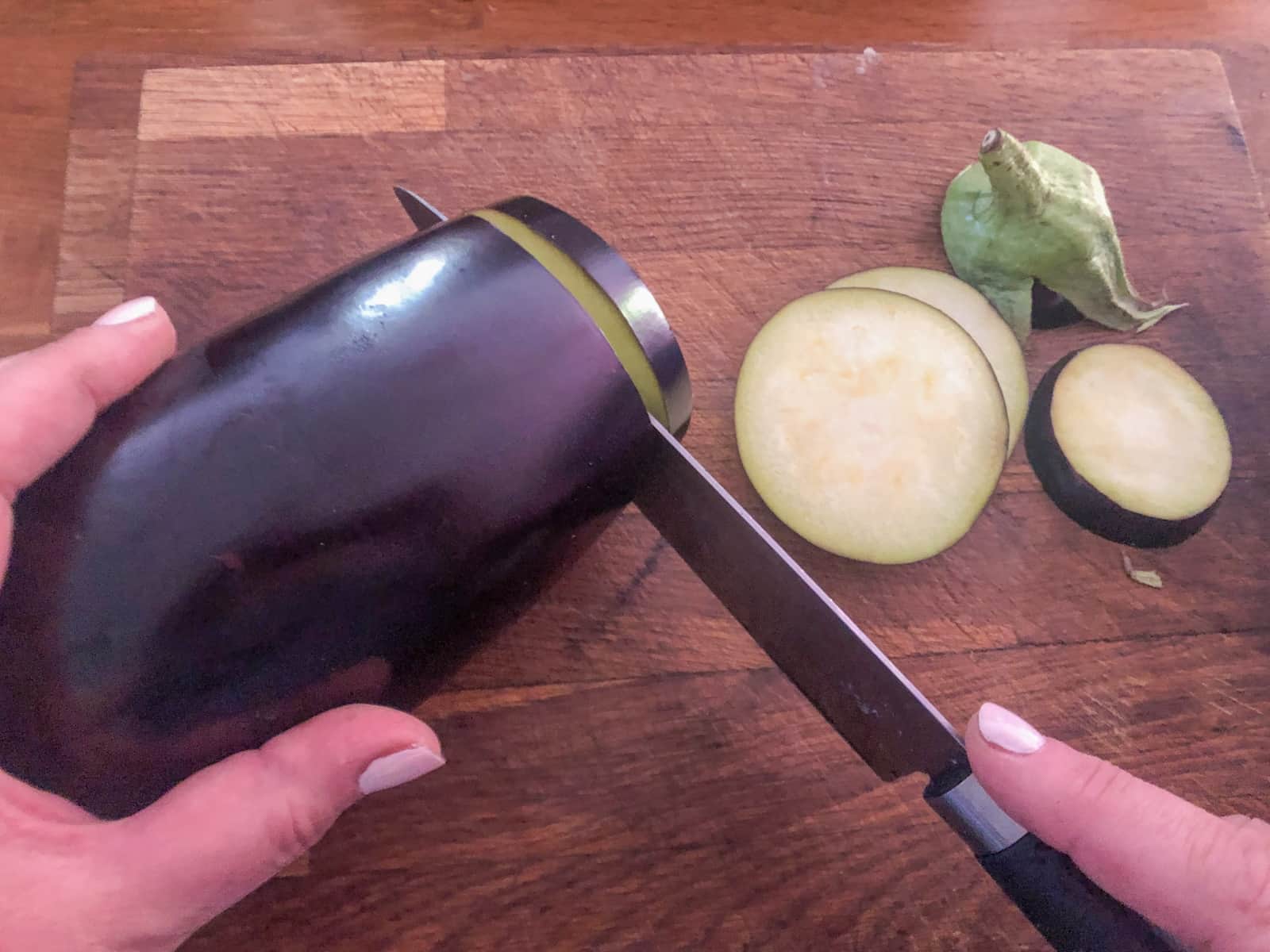 Aubergines being sliced on a wooden board