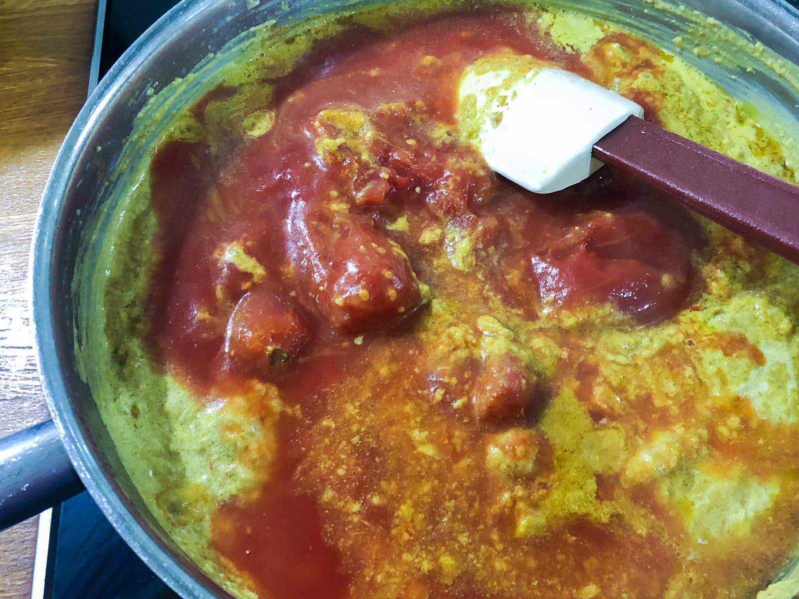 Adding tomatoes to a vegetarian curry sauce.