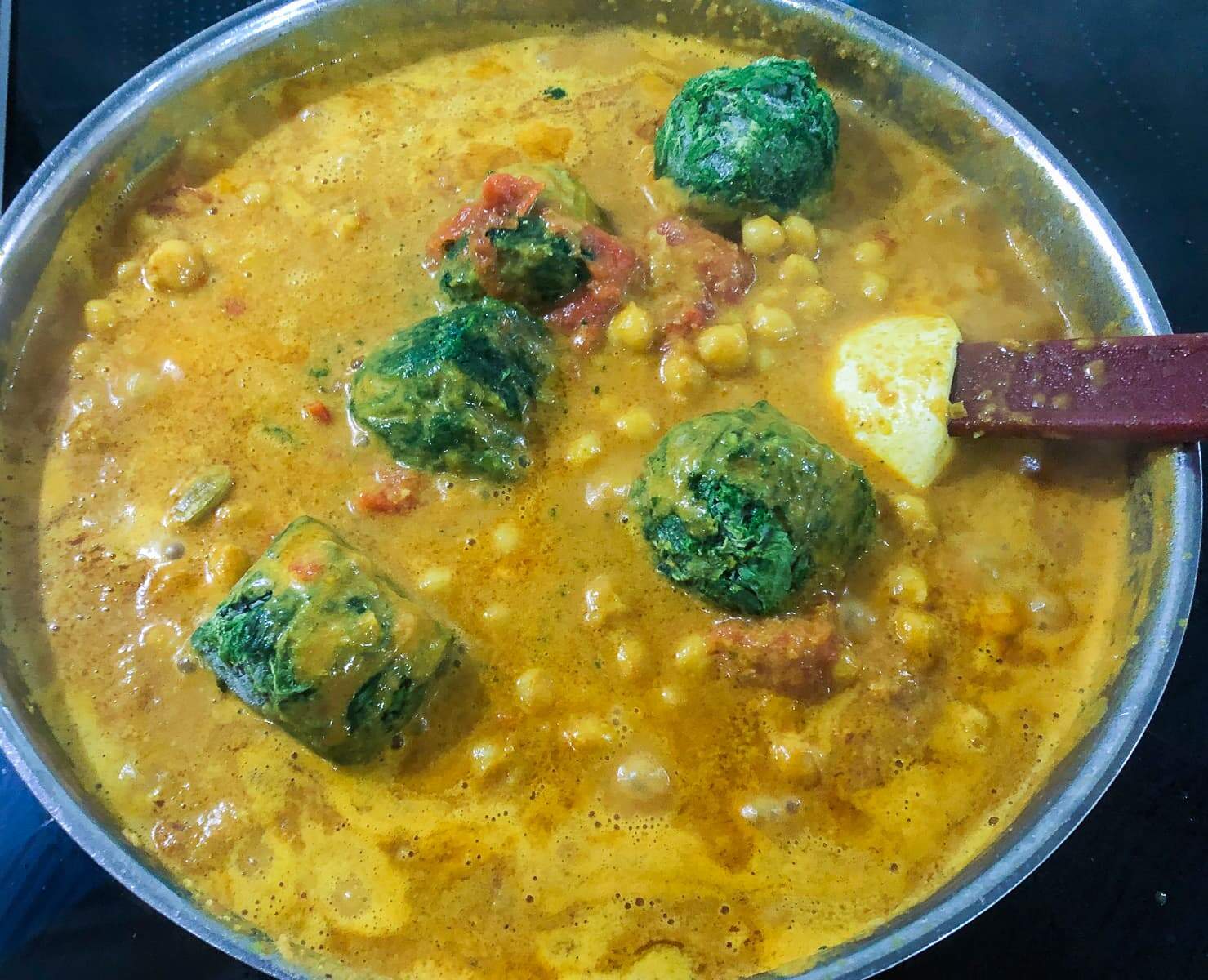 Spinach being added to a vegetarian curry sauce