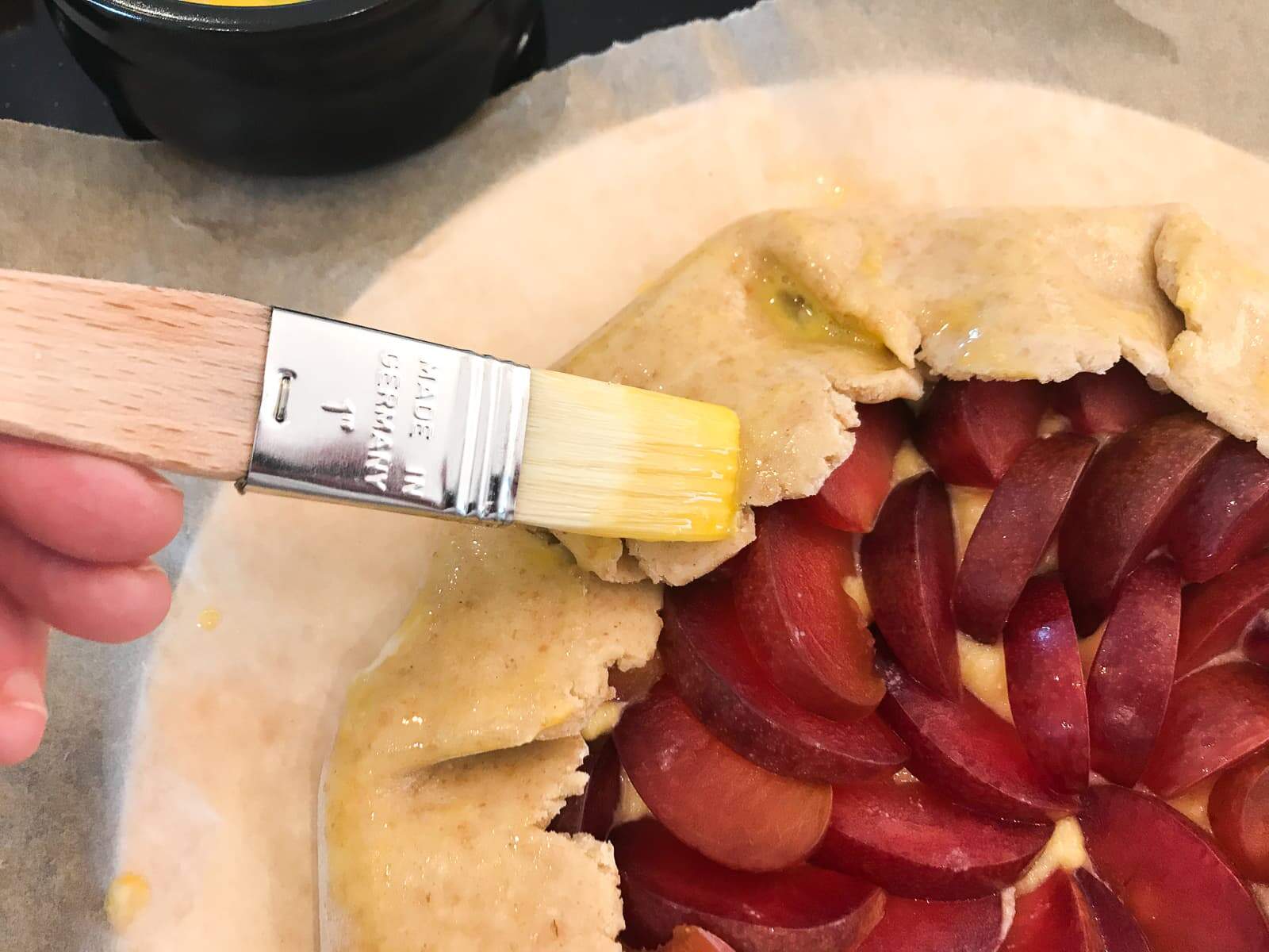 a pastry brush adding an egg wash over top of a tart pastry.