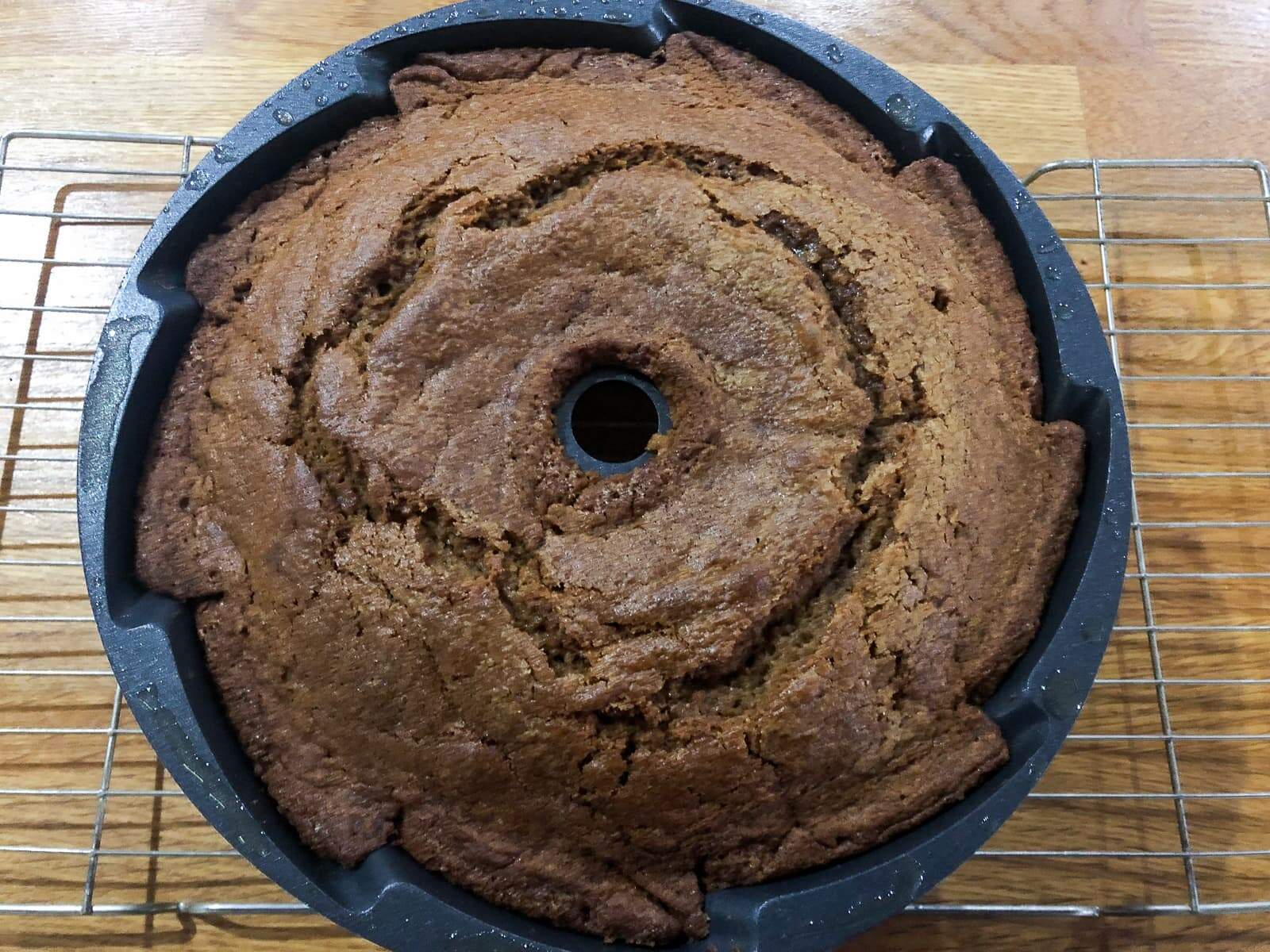 A pumpkin spice cake in a bundt tin just out of the oven on a wire rack cooling.