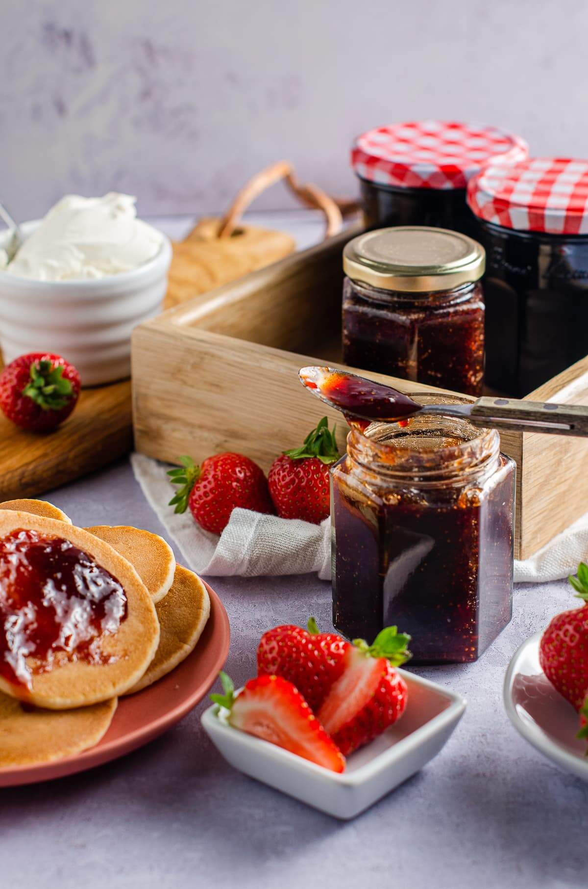 Strawberries and jam with pancakes as a breakfast scene.