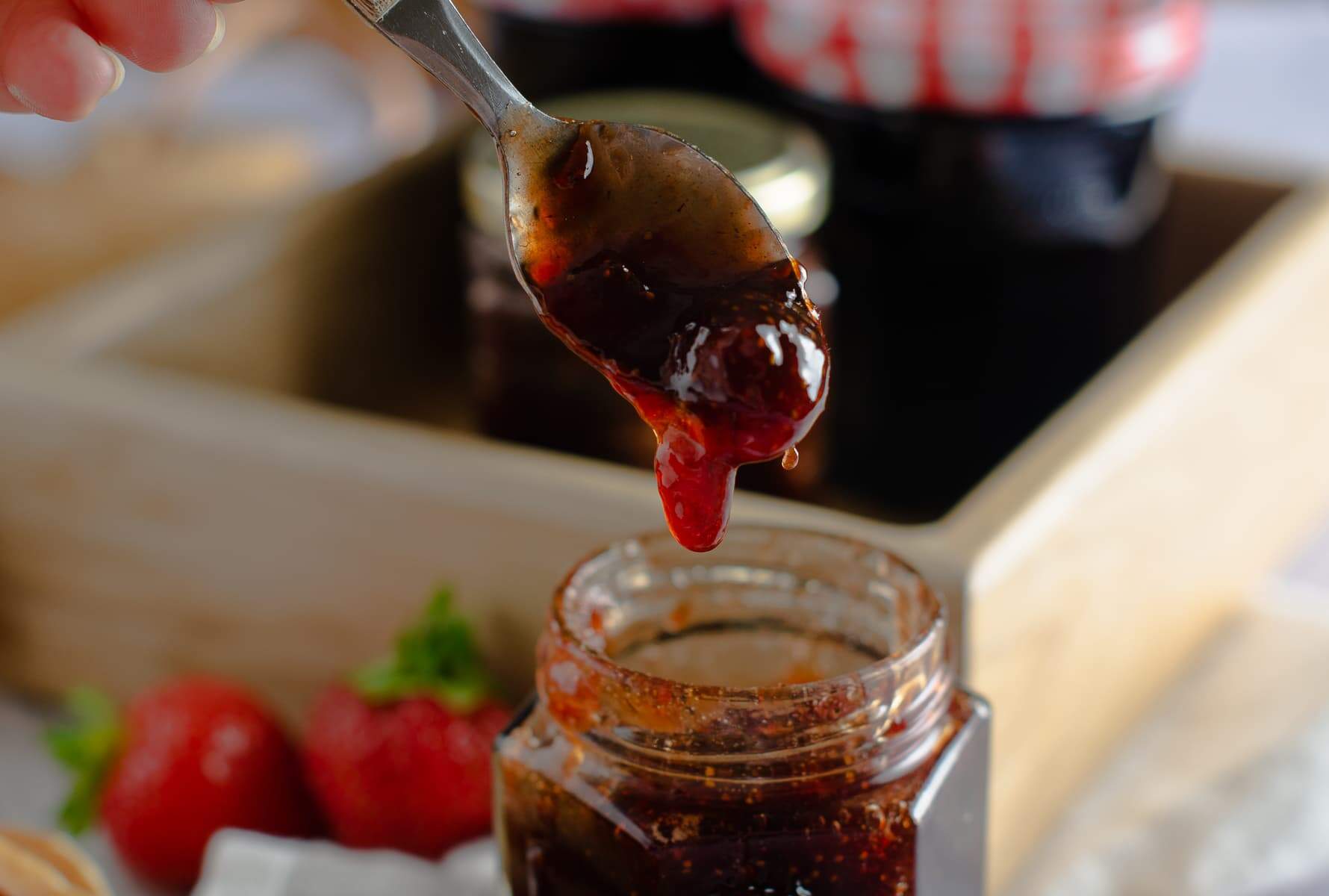 Homemade jam dropping from a spoon back into the jar.