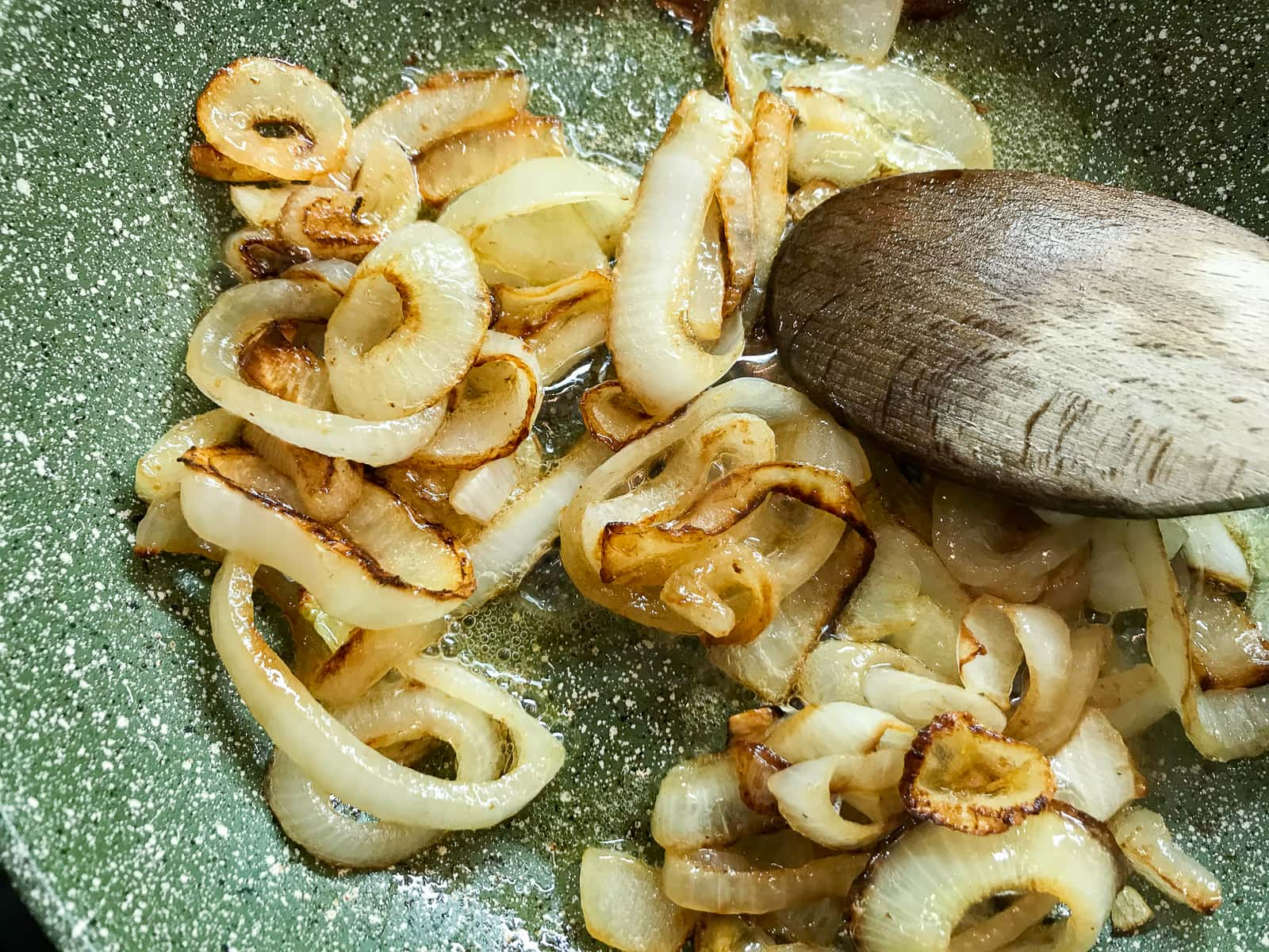 Sliced onions frying in a pan.