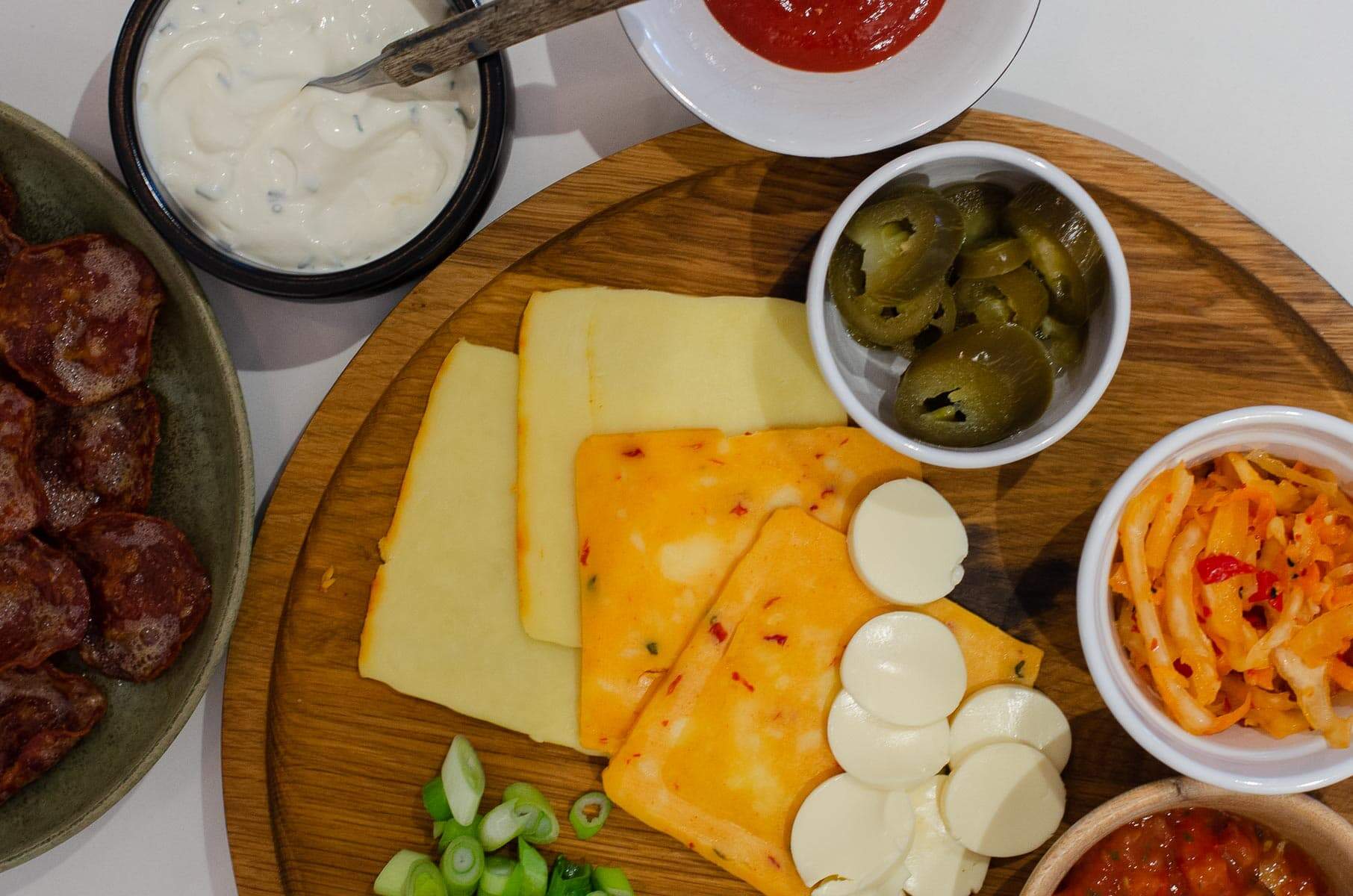 spring onions, cheese, salsas and mustards for toppings to add to hot dogs.