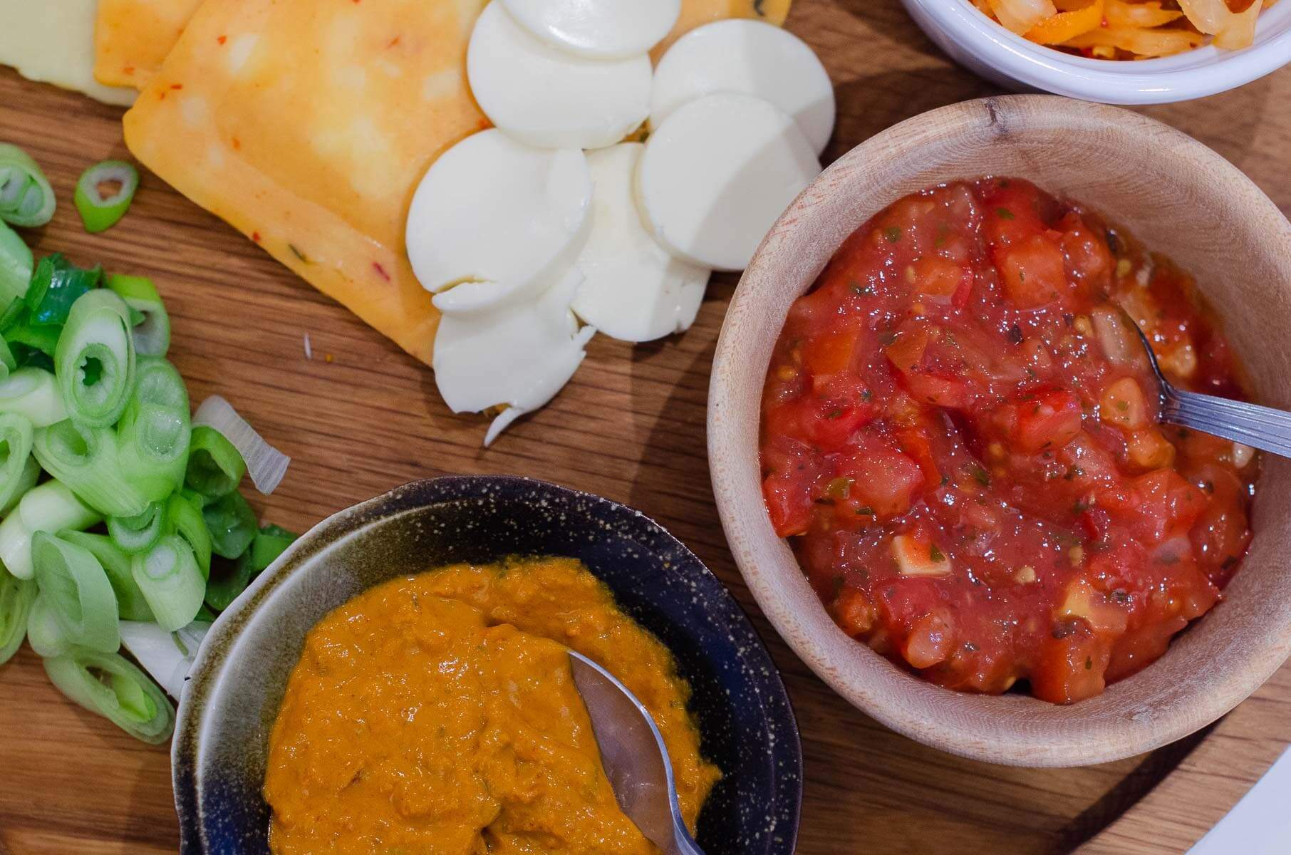 sliced spring onions, mustard and salsa in small bowls.